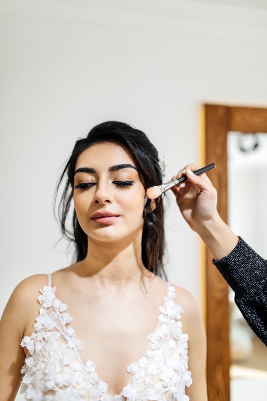 la mariee recoit les dernieres retouches de maquillage avant sa ceremonie de mariage dans un cadre elegant