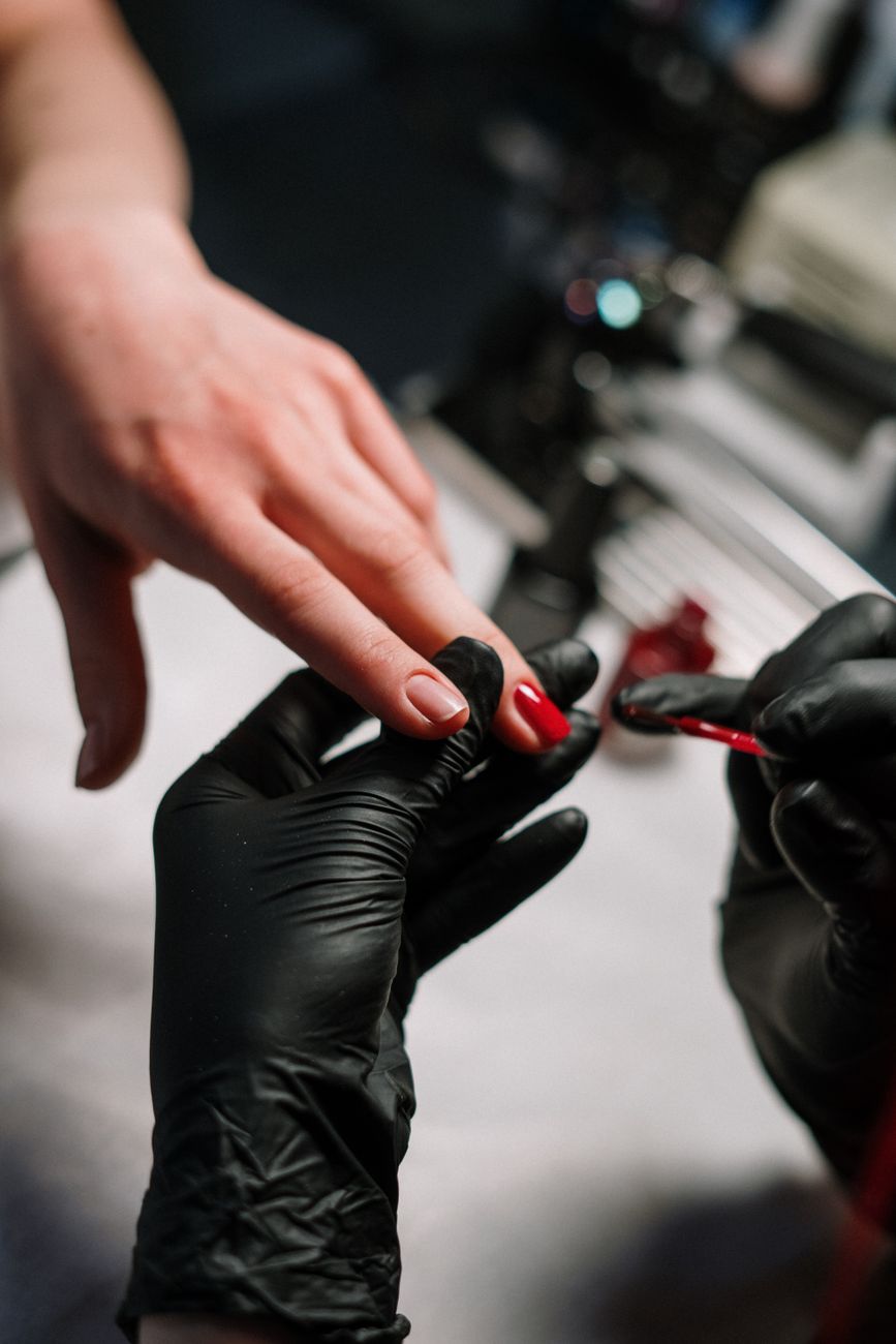 gros plan d un artiste des ongles appliquant du vernis avec precision en utilisant des gants noirs dans un salon
