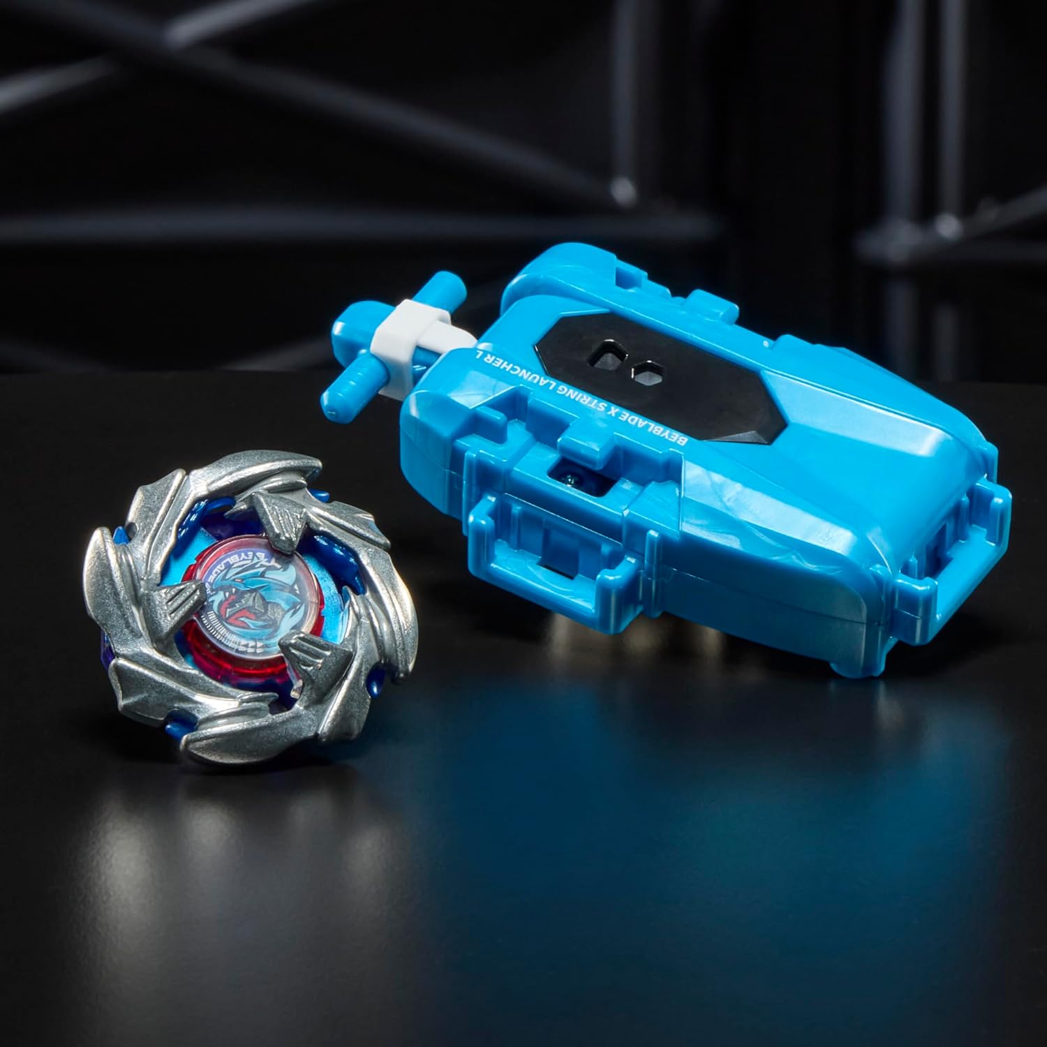 Toupie et lanceur posés sur une surface noire brillante