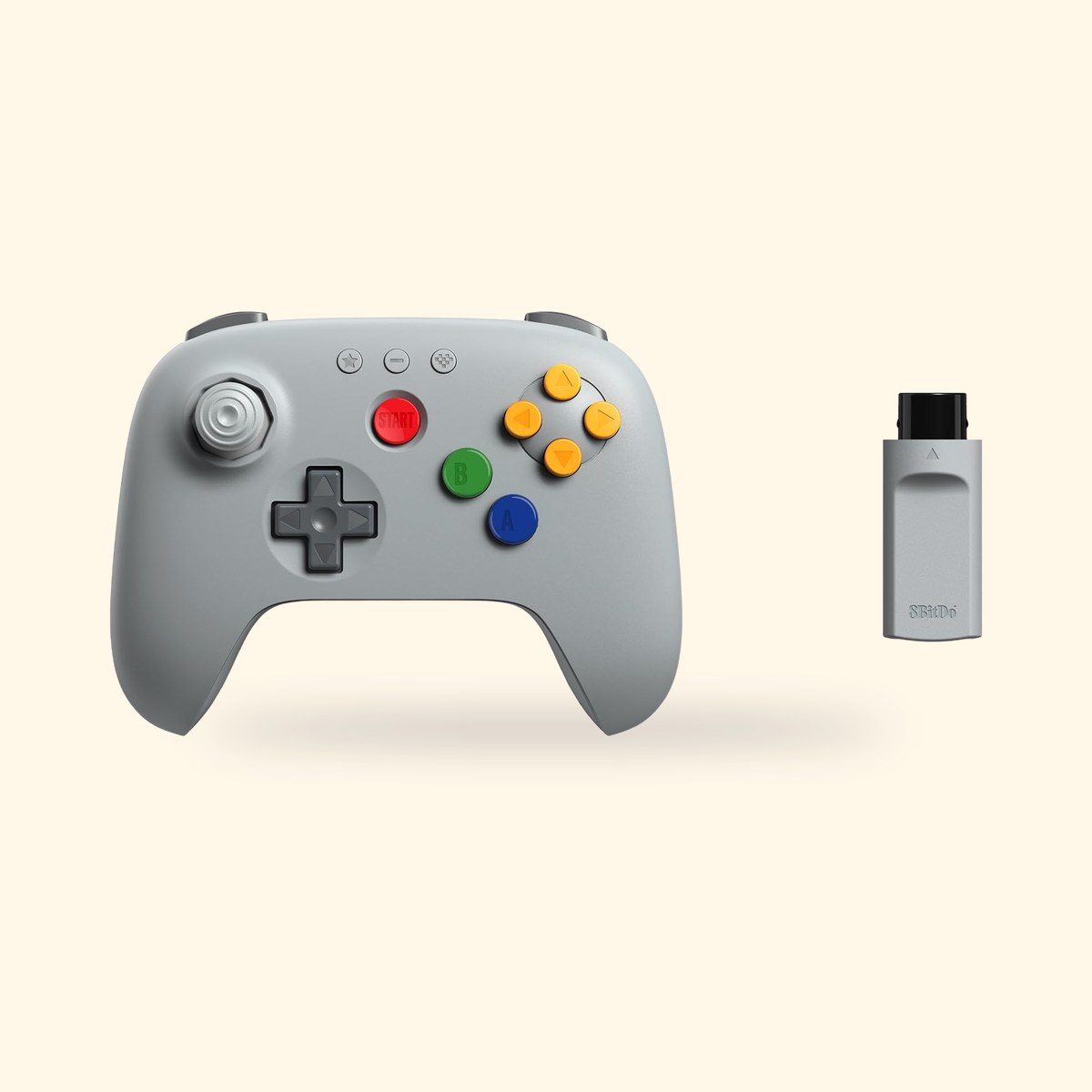 Manette N64 sans fil 8BitDo 64 grise et son récepteur, sur fond crème