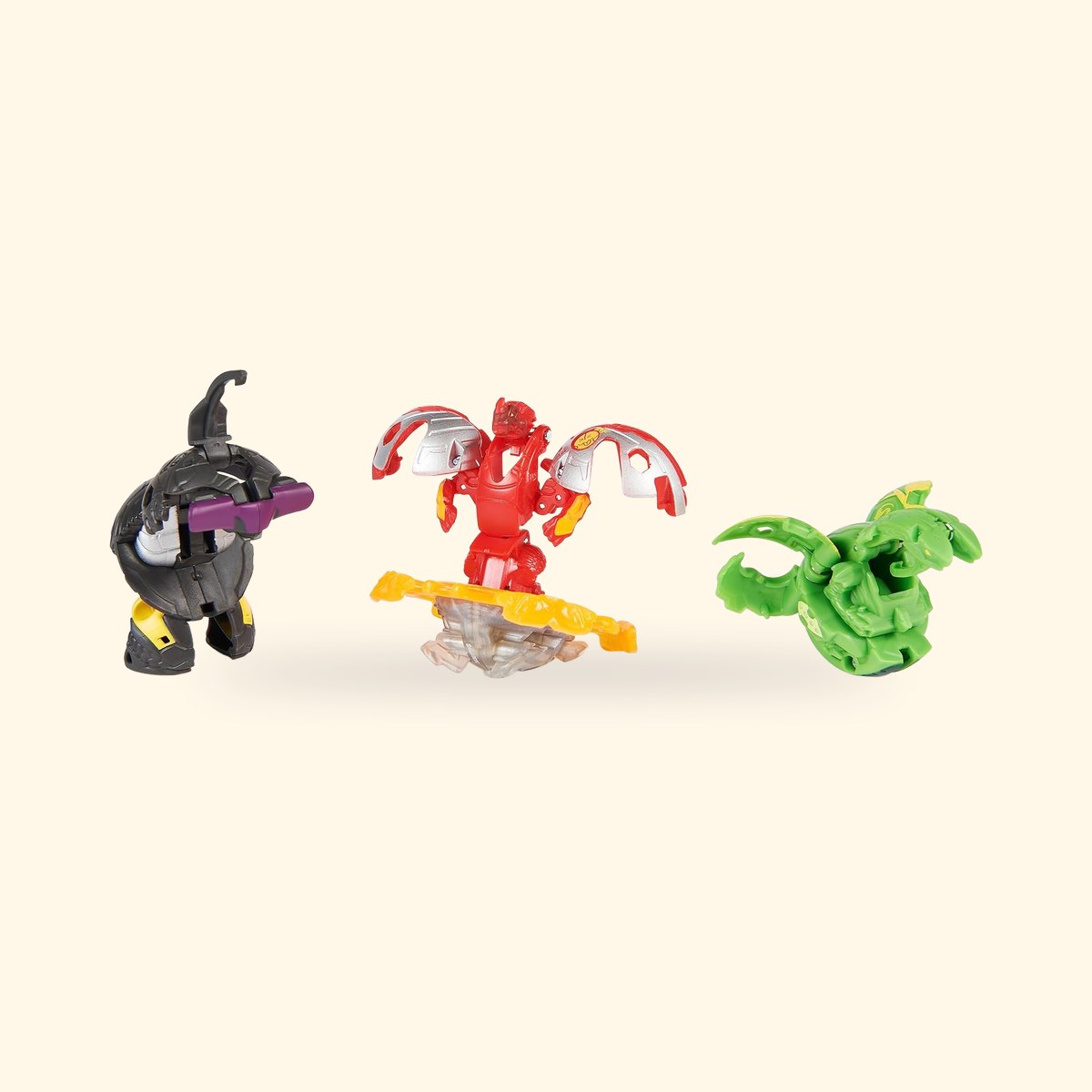 Trois Bakugan déployés : Hammerhead noir, Dragonoid rouge sur son anneau et Nillious vert, sur fond crème