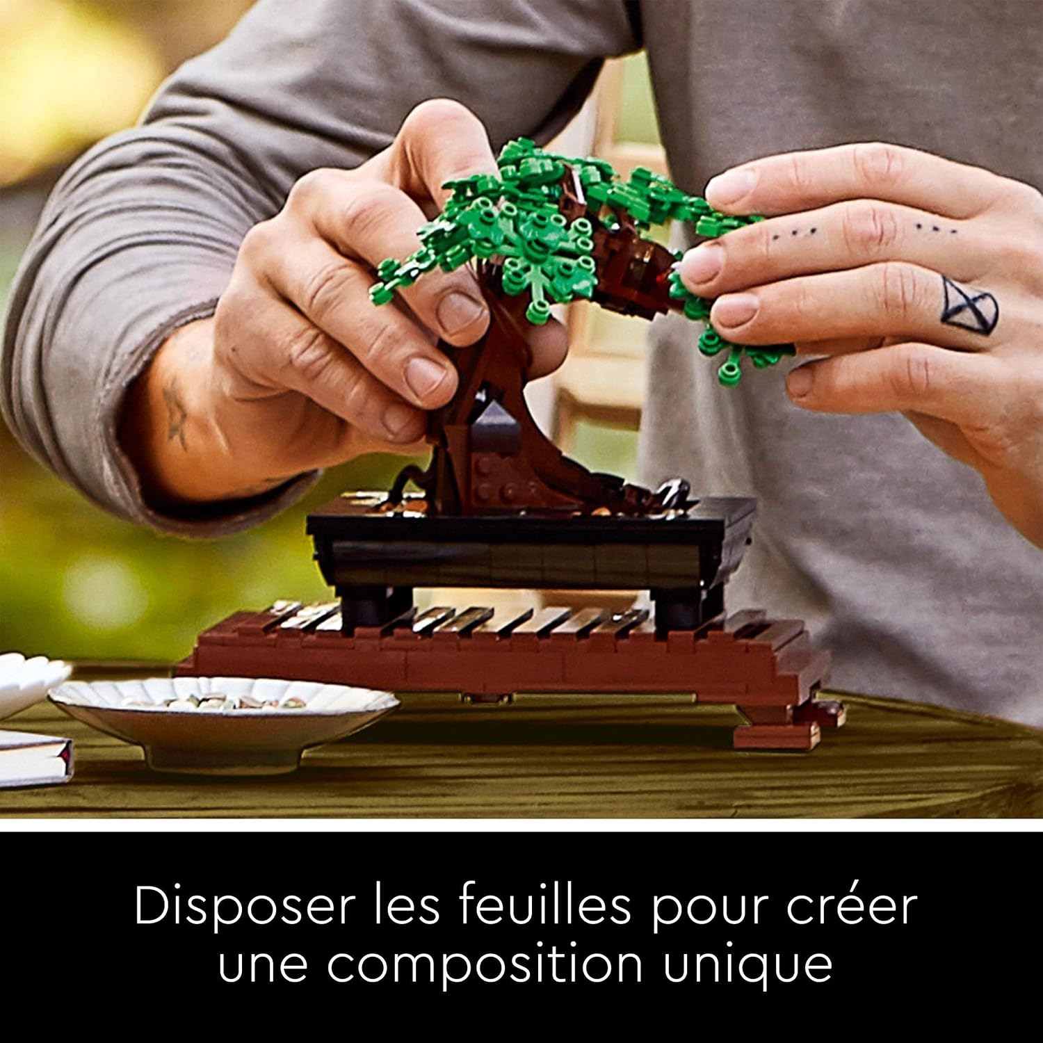 Mains qui disposent le feuillage vert du bonsaï LEGO