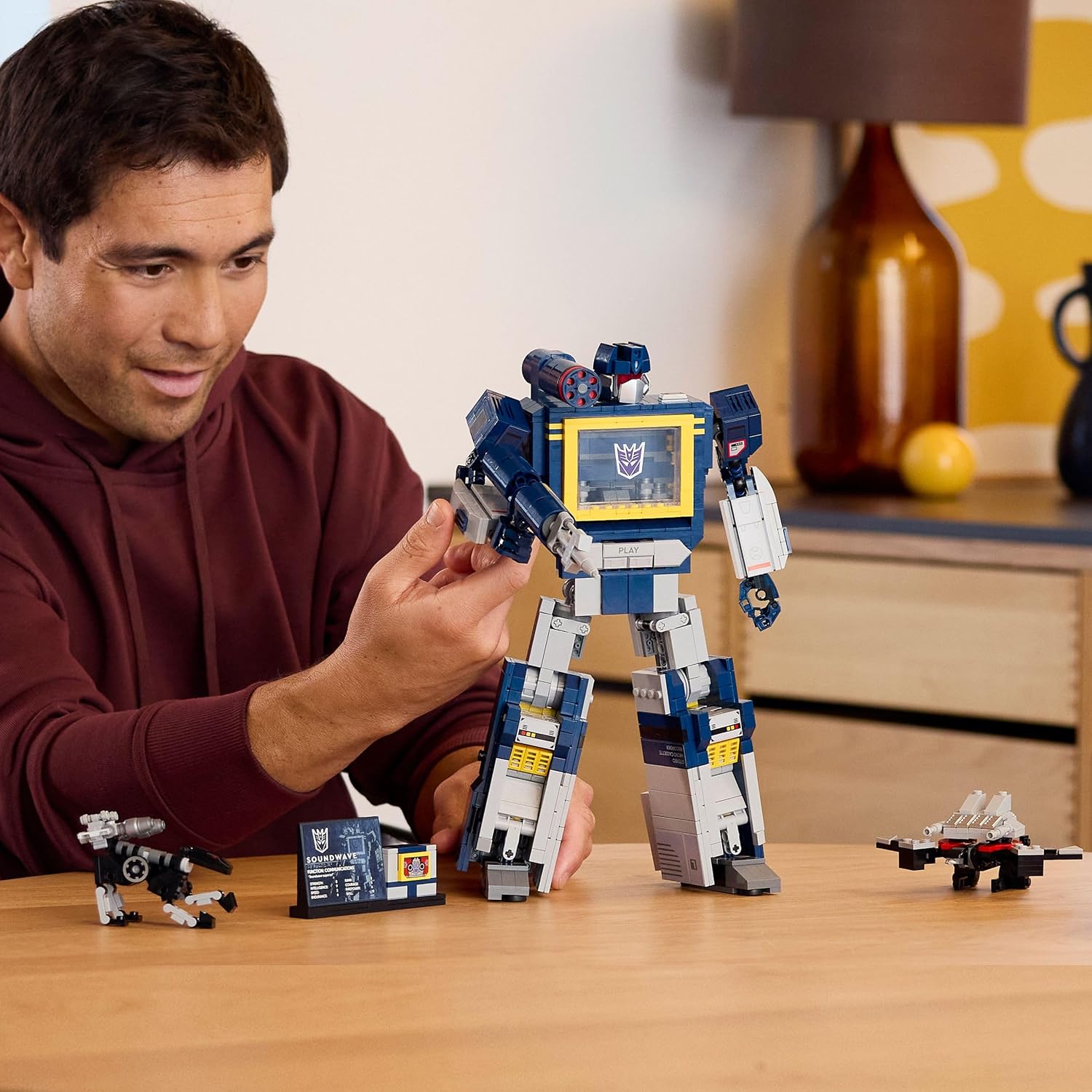 Homme qui manipule Soundwave sur une table, à côté de Ravage, de la plaque et de Laserbeak