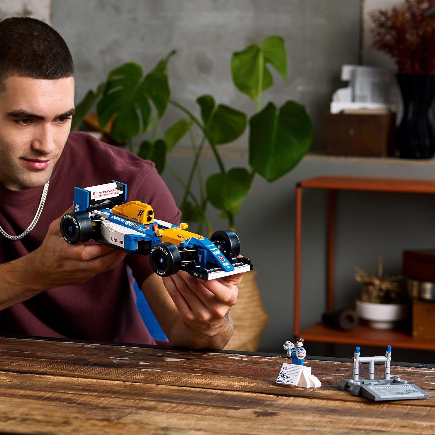 Jeune homme qui tient la Williams LEGO, minifigurine et présentoir sur la table