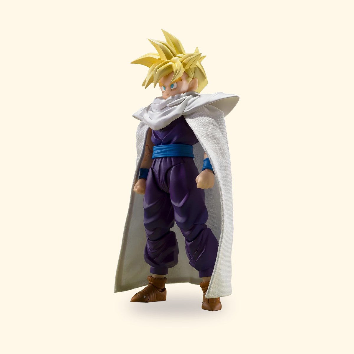 Figurine S.H.Figuarts de Gohan Super Saiyan en tenue violette et cape blanche, sur fond crème