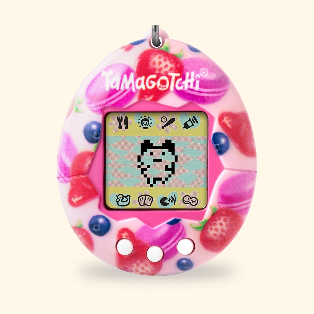 Tamagotchi Original Berry Delicious à coque rose décorée de fraises et de macarons, sur fond crème