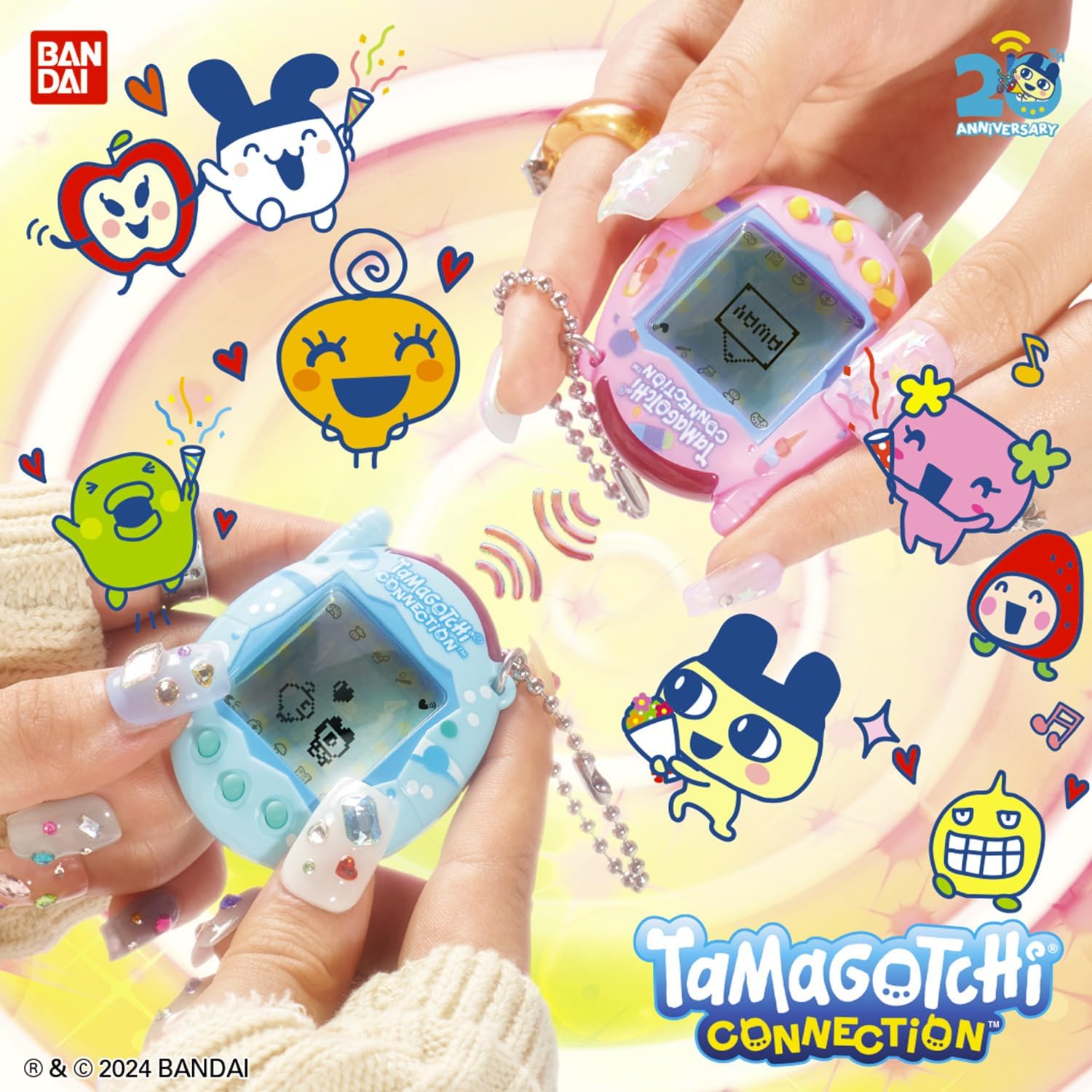 Mains tenant deux Tamagotchi Connection, rose et bleu, face à face, logo des 20 ans