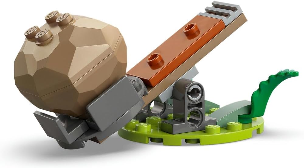 Gros plan sur la catapulte LEGO chargée dun rocher, sur un socle dherbe