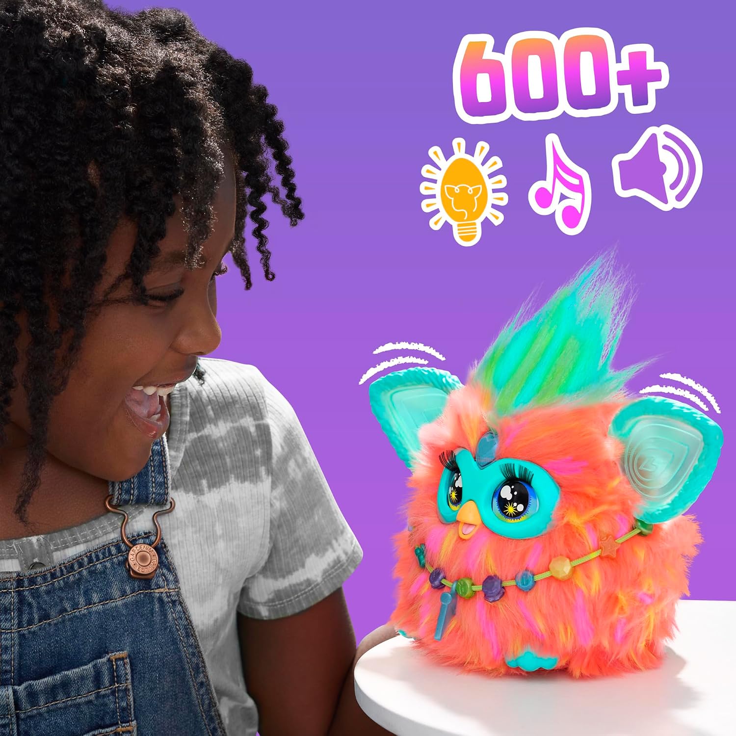 Enfant qui rit devant le Furby, visuel 600+ avec icônes de lumière, de musique et de son