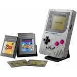 Game Boy LEGO sur son support, cartouches Zelda et Super Mario Land et deux écrans posés devant, sur fond blanc