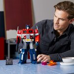 Homme qui regarde Optimus Prime en robot posé sur une table