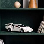Countach LEGO blanche exposée sur une étagère vert foncé, à côté de livres