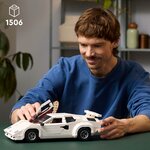 Homme qui ouvre la portière en élytre de la Countach LEGO posée sur une table