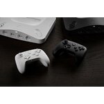 Manettes 8BitDo 64 blanche et noire posées devant une console
