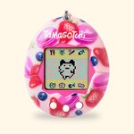 Tamagotchi Original Berry Delicious à coque rose décorée de fraises et de macarons, sur fond crème