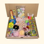 Box en carton ouverte garnie de bonbons rétro : soucoupes, colliers, sucettes, roudoudous, sur fond crème
