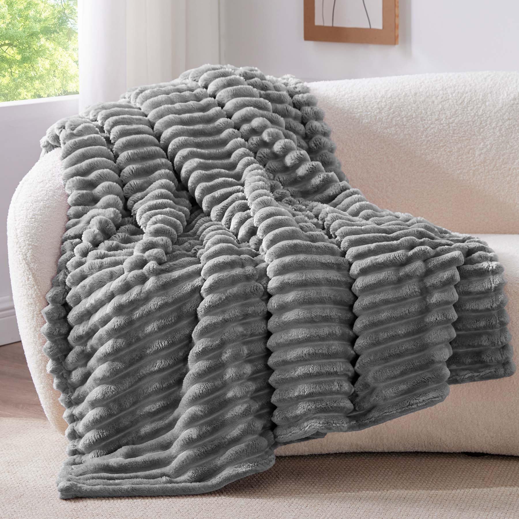 Plaid polaire gris doux posé sur un canapé