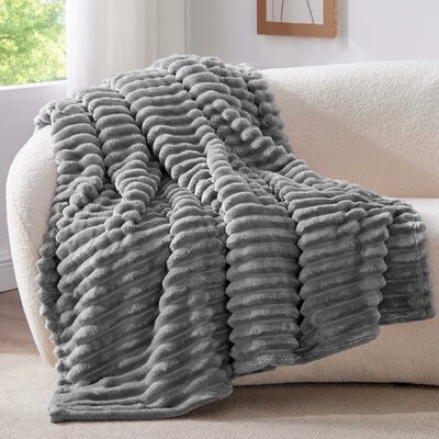 Plaid polaire gris doux posé sur un canapé