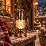 Lanterne tempête LED cuivrée allumée sur un banc enneigé devant un chalet décoré pour Noël