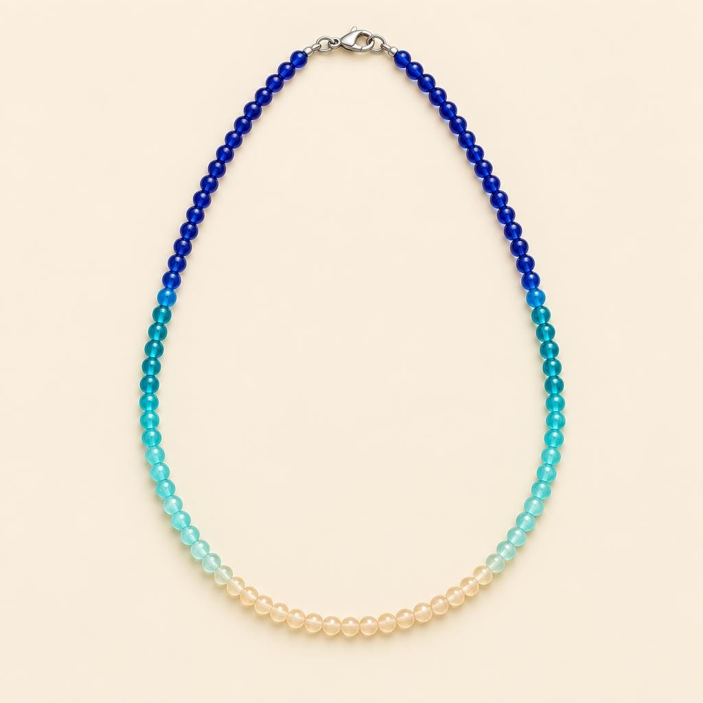 collier-en-perles-de-verre-bleu-ocean-et-sable-sur-fond-crem-2