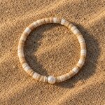 Bracelet en perles heishi couleur sable avec une perle d’eau douce, posé sur le sable