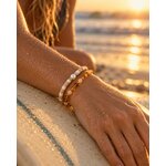 Deux bracelets en perles portés au poignet sur le rail d’une planche de surf