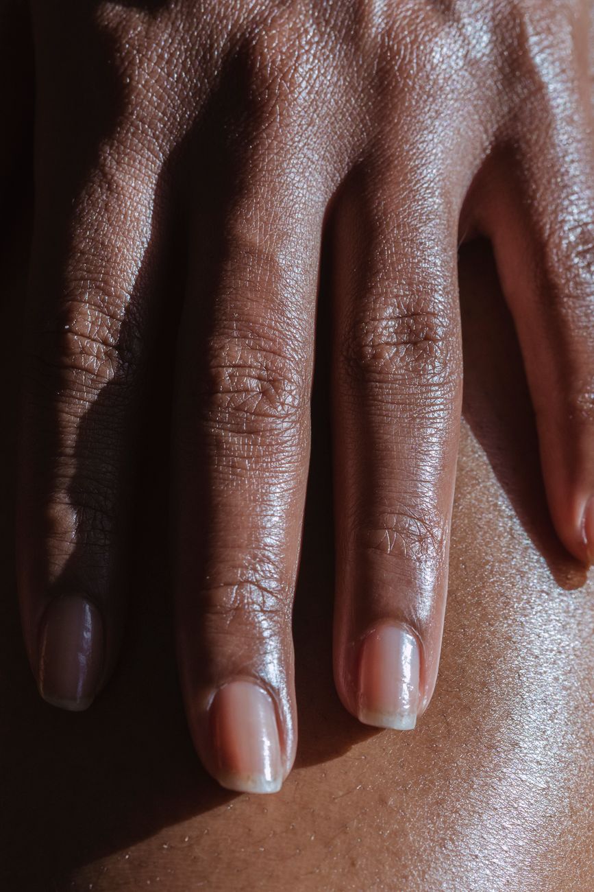 un gros plan d une main adulte reposant sur la peau mettant en valeur la texture et le ton de la peau dans un eclairage naturel