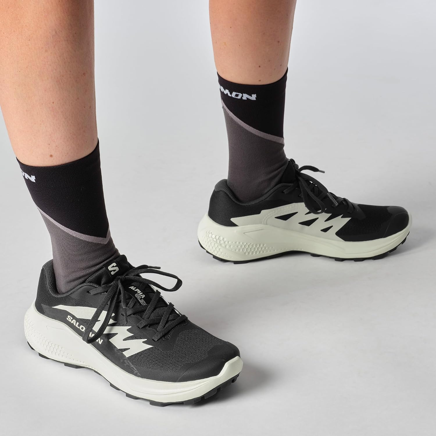 Runner con Salomon Alphaglide nere ai piedi e calze alte
