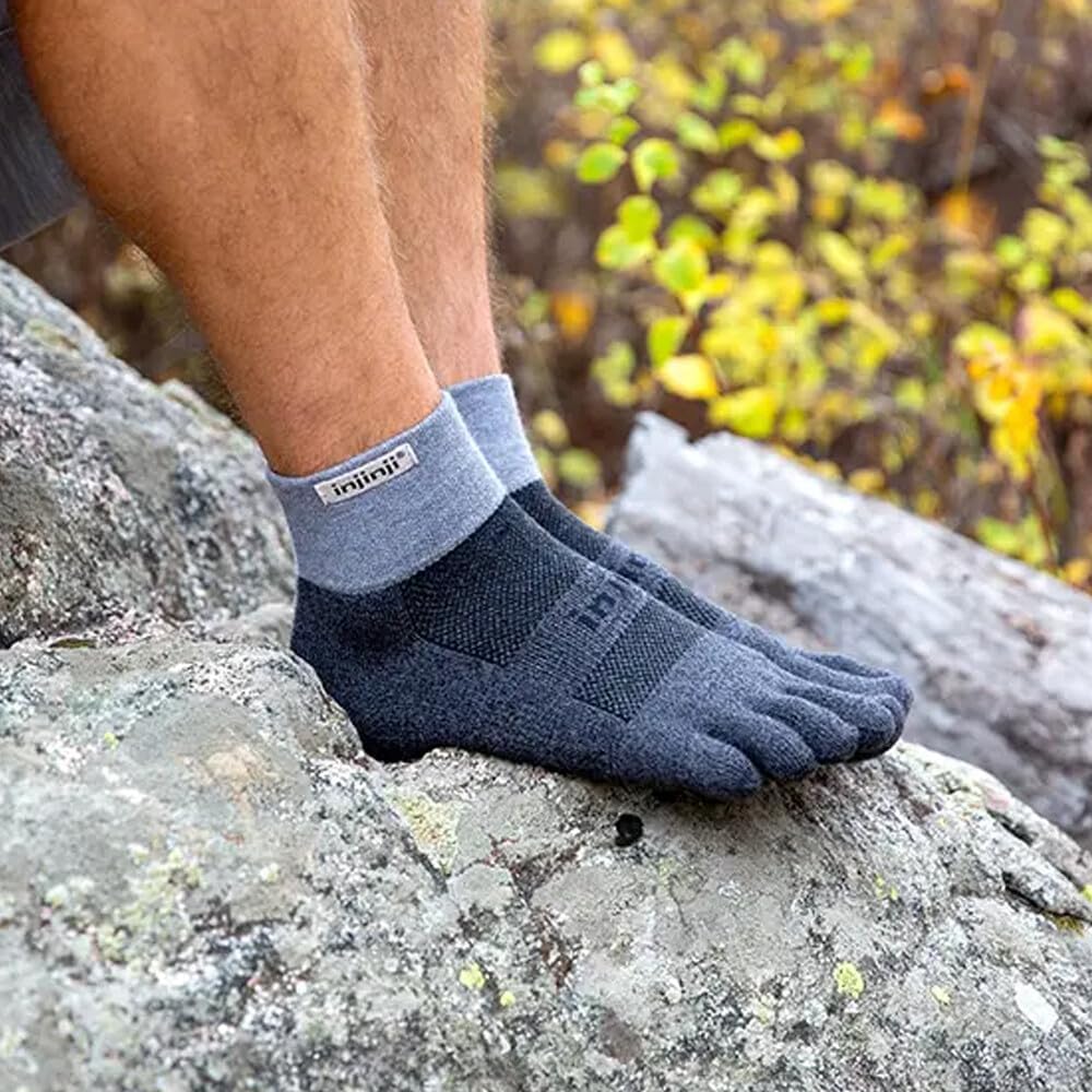 Piedi con calze a 5 dita Injinji blu appoggiati su una roccia