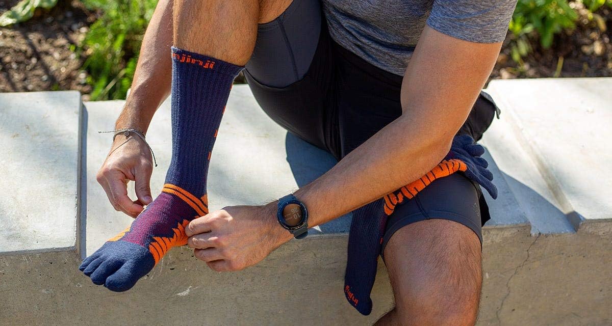 Runner che indossa una calza a 5 dita Injinji seduto su un muretto