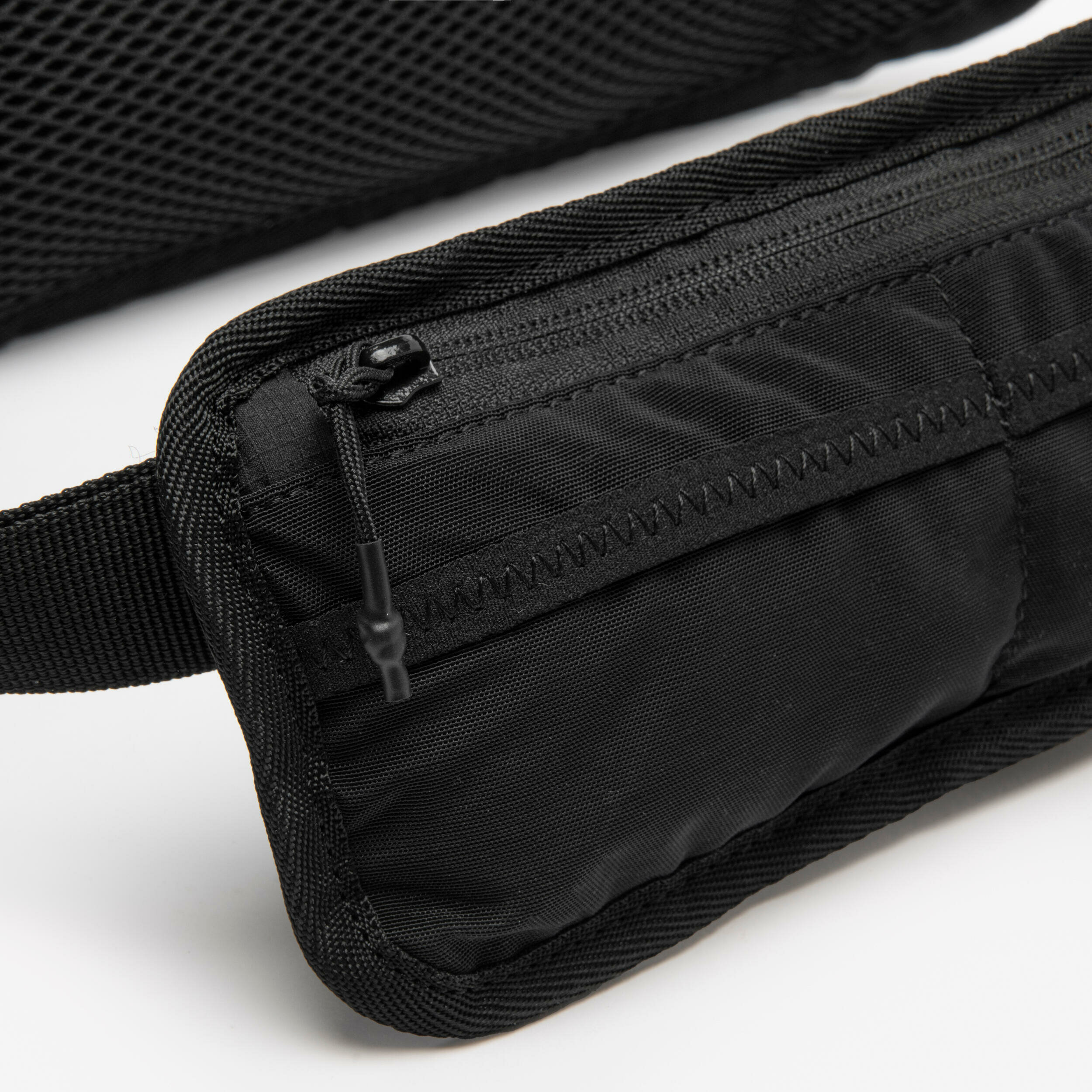 Primo piano della tasca frontale con zip della cintura Kiprun in tessuto ripstop nero