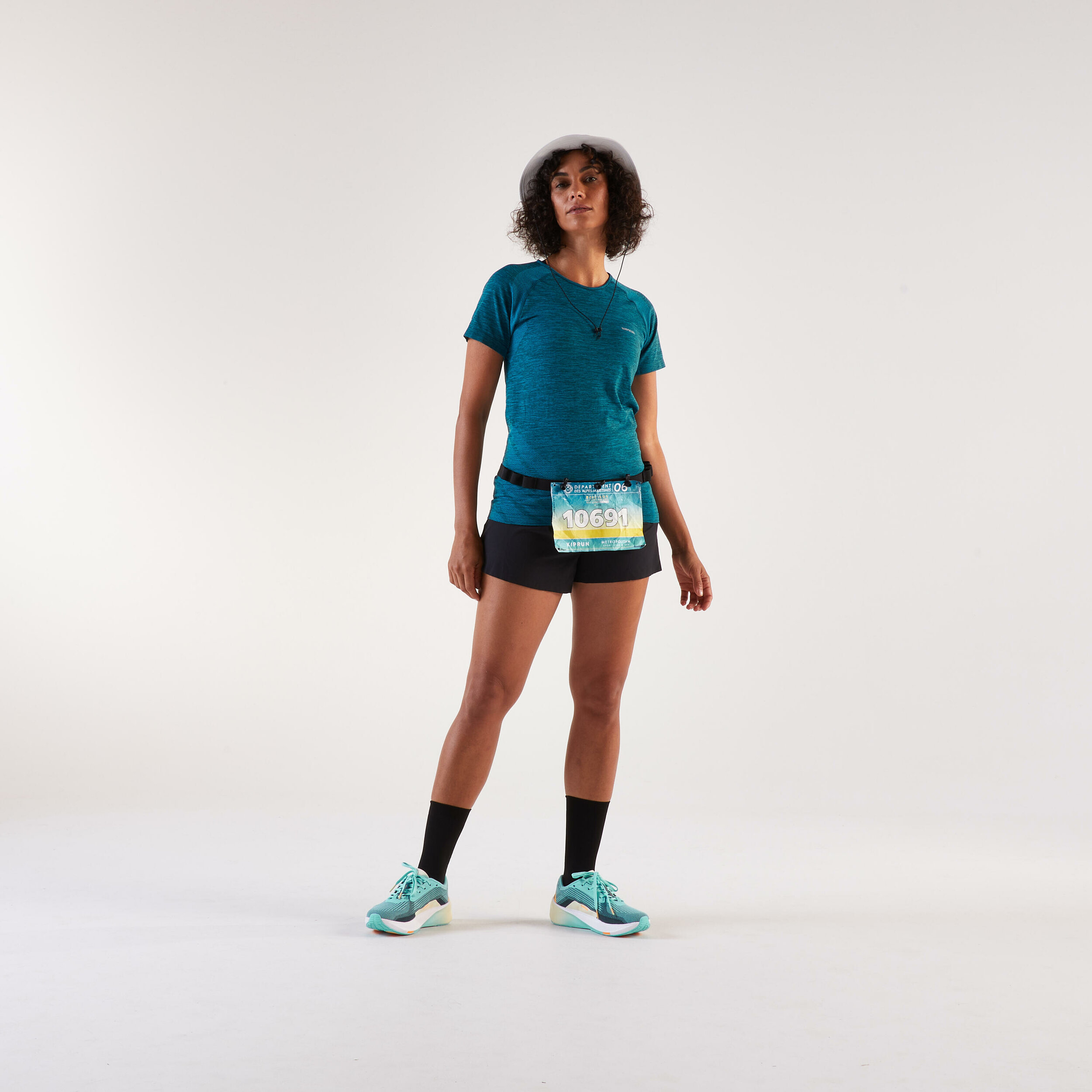 Runner vista di fronte con il pettorale appeso alla cintura Kiprun sopra i pantaloncini neri