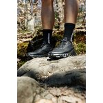Runner con Salomon Alphacross 5 nere in piedi su una roccia nel bosco