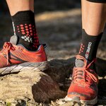 Calza Compressport nera e rossa indossata con scarpa da trail su roccia
