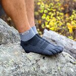 Piedi con calze a 5 dita Injinji blu appoggiati su una roccia