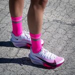 Calze da corsa NORTEI rosa fluo ai piedi di un runner su asfalto