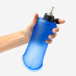 Mano che tiene la soft flask Kiprun 500 ml blu con il pollice nel passante