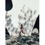 Runner che corre davanti a un muro bianco con la giacca Kiprun Run Rain 900 marrone