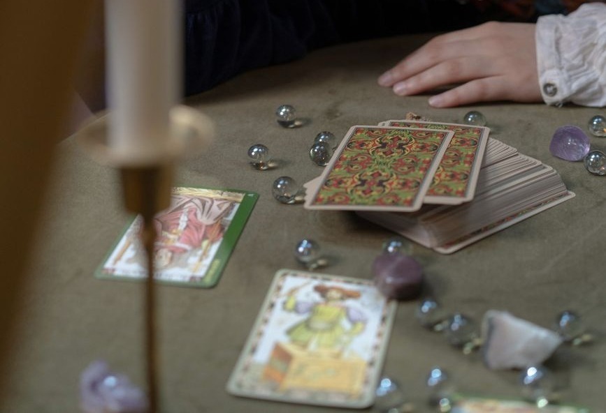 une femme pratiquant la lecture de tarot entouree de bougies et de pierres precieuses evoquant une atmosphere mystique