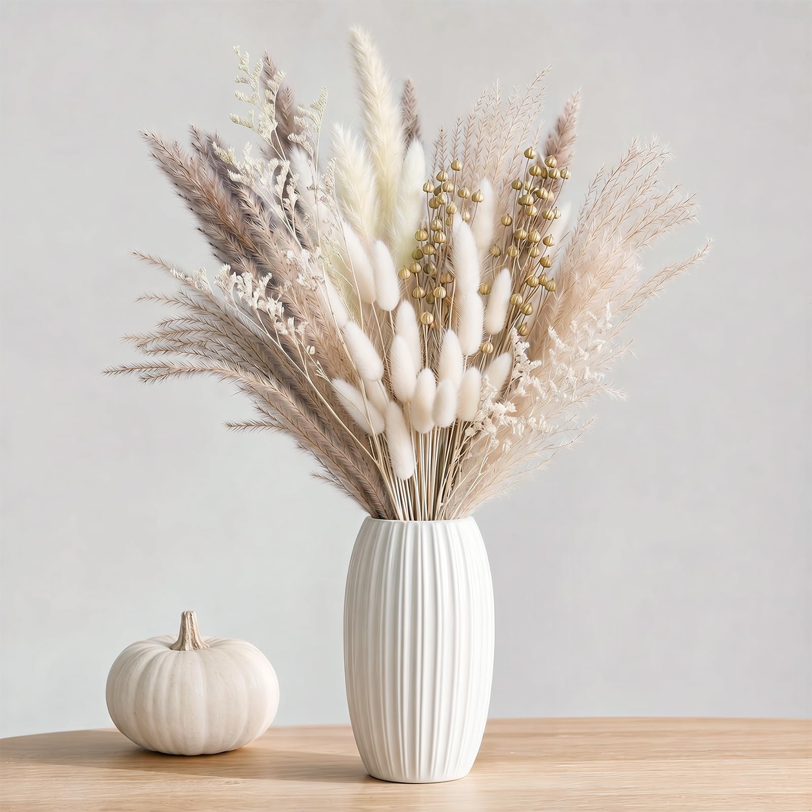 Trockenblumenstrauß aus Pampasgras und Bunny Tails in Weiß und Beige in weißer Rillenvase neben Kürbis