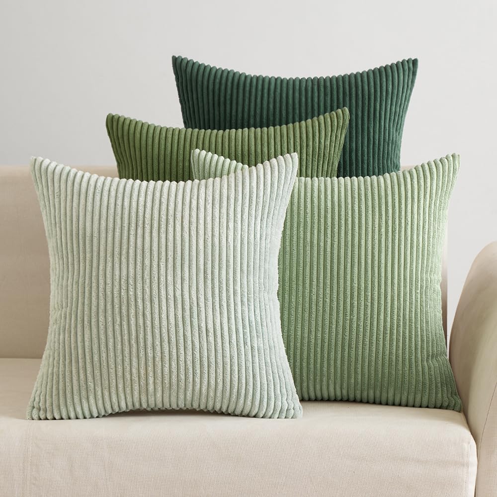 Vier Cordkissen in Grüntönen von Mint bis Dunkelgrün auf einem cremefarbenen Sofa
