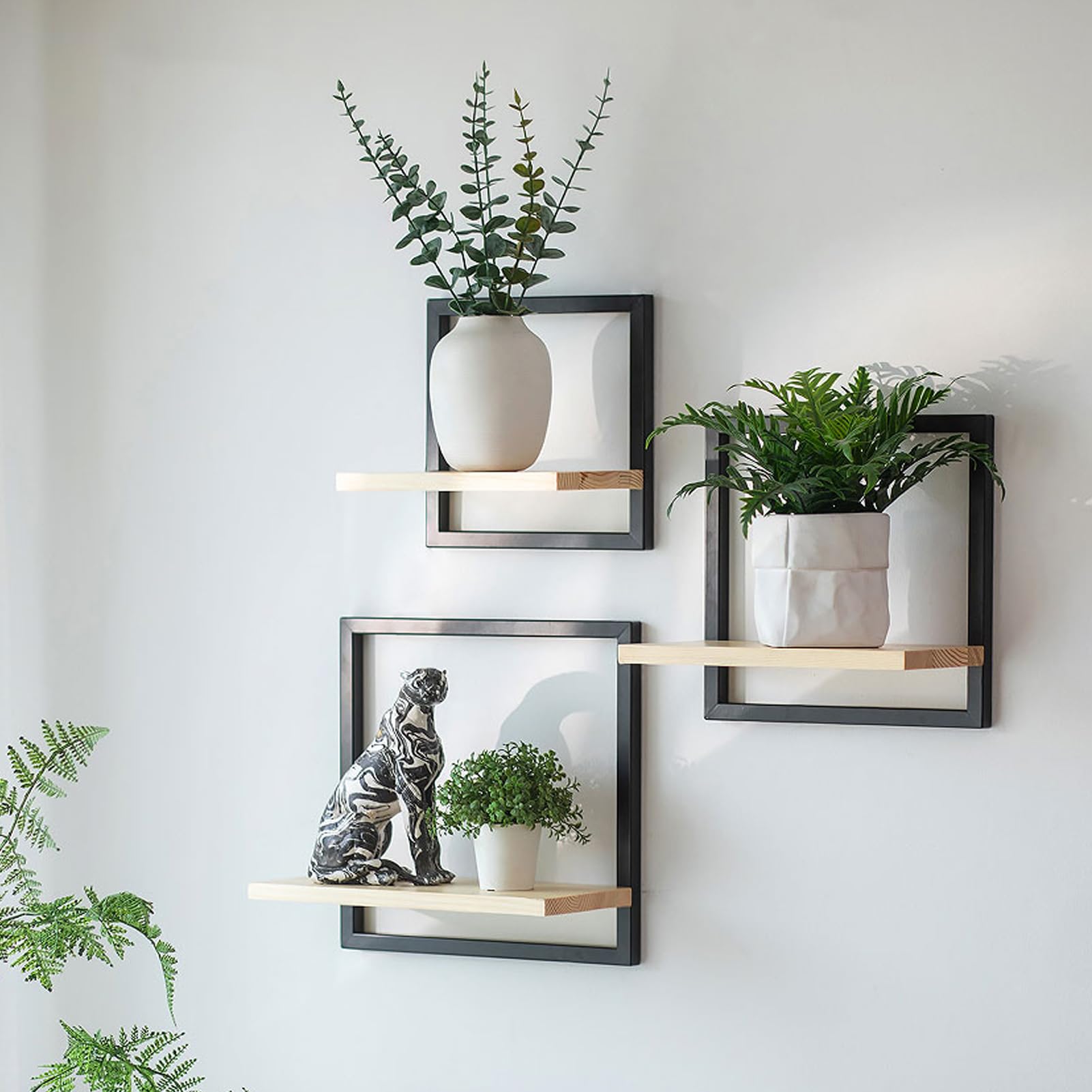 Drei kleine naturfarbene Holz-Wandregale, versetzt an der Wand montiert und mit Deko bestückt