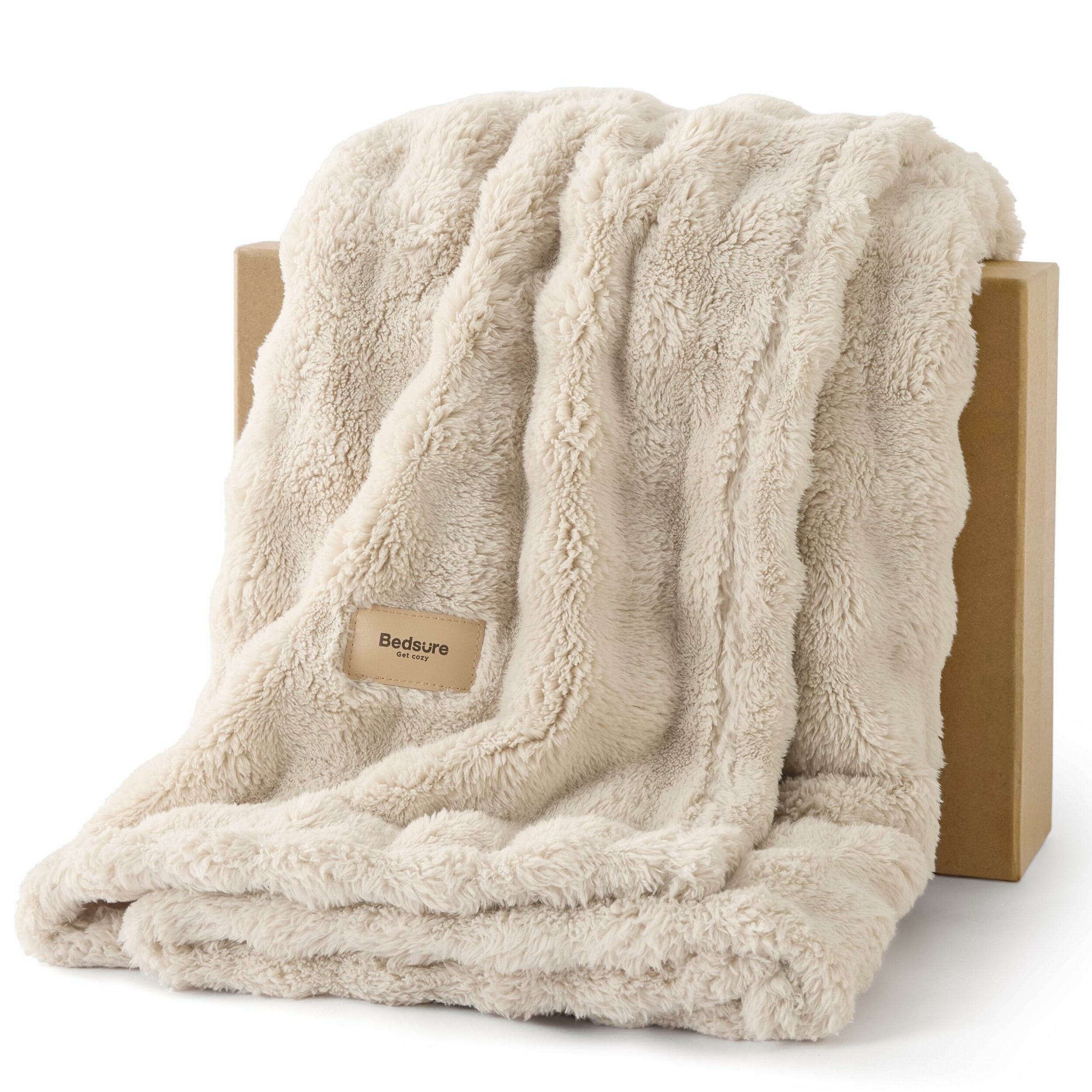 Beige Kuscheldecke mit Bubble-Noppenstruktur, locker über eine Holzkante drapiert