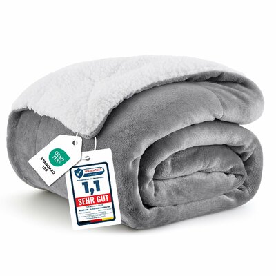 Graue Kuscheldecke aus Flanell mit weißer Sherpa-Rückseite, zusammengerollt, mit Etiketten
