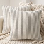 Zwei beige Cordkissen mit Längsrippen auf einem hellen Sofa vor einer Strickdecke