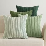 Vier Cordkissen in Grüntönen von Mint bis Dunkelgrün auf einem cremefarbenen Sofa