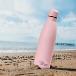 Gourde isotherme rose posée sur une plage