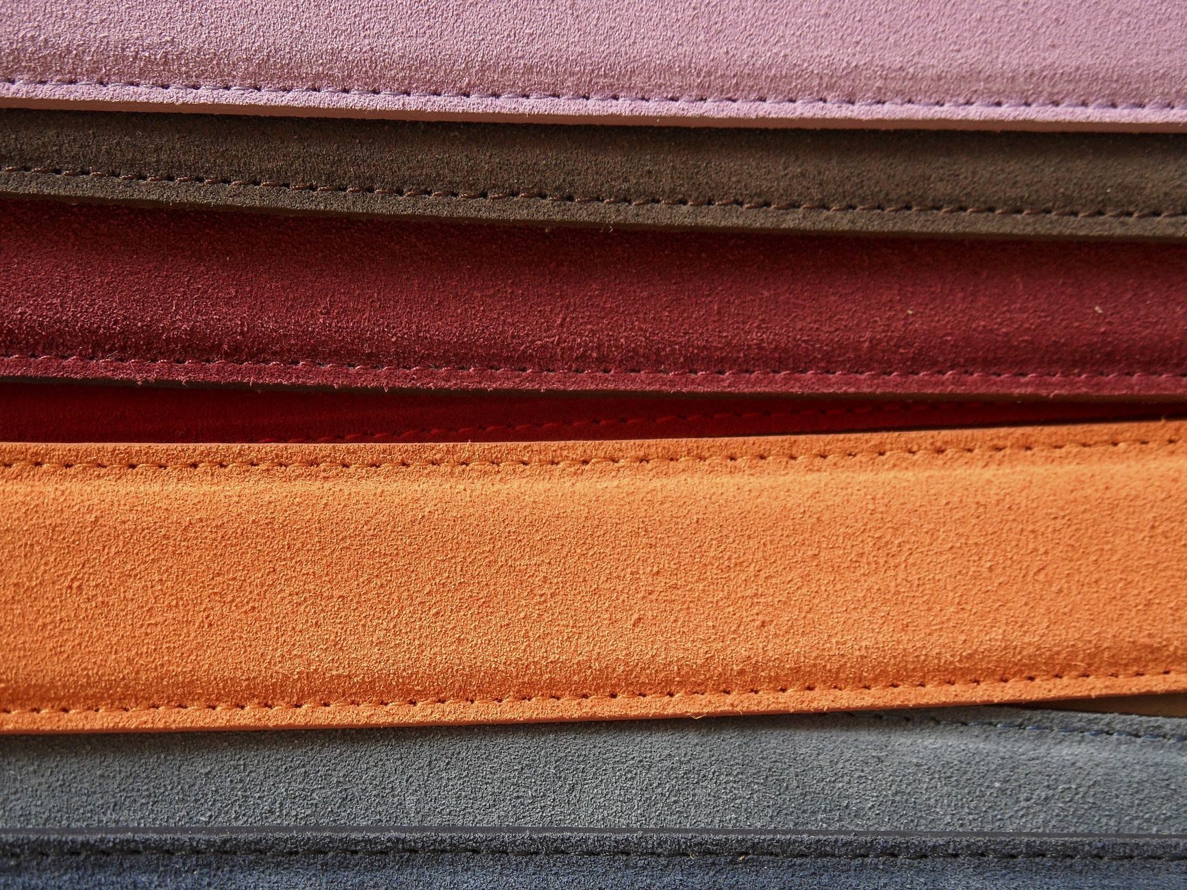 Gros plan sur des ceintures en cuir colorées présentant des coutures détaillées