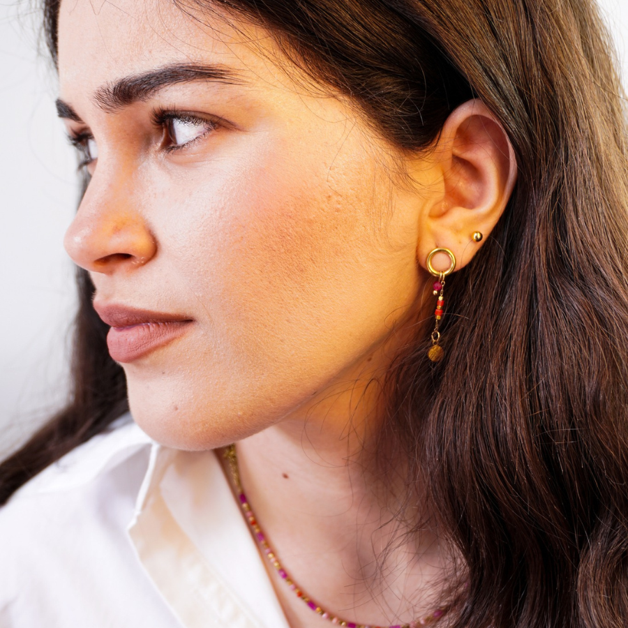 Jeune femme avec de jolies boucles doreilles dorées et rouge