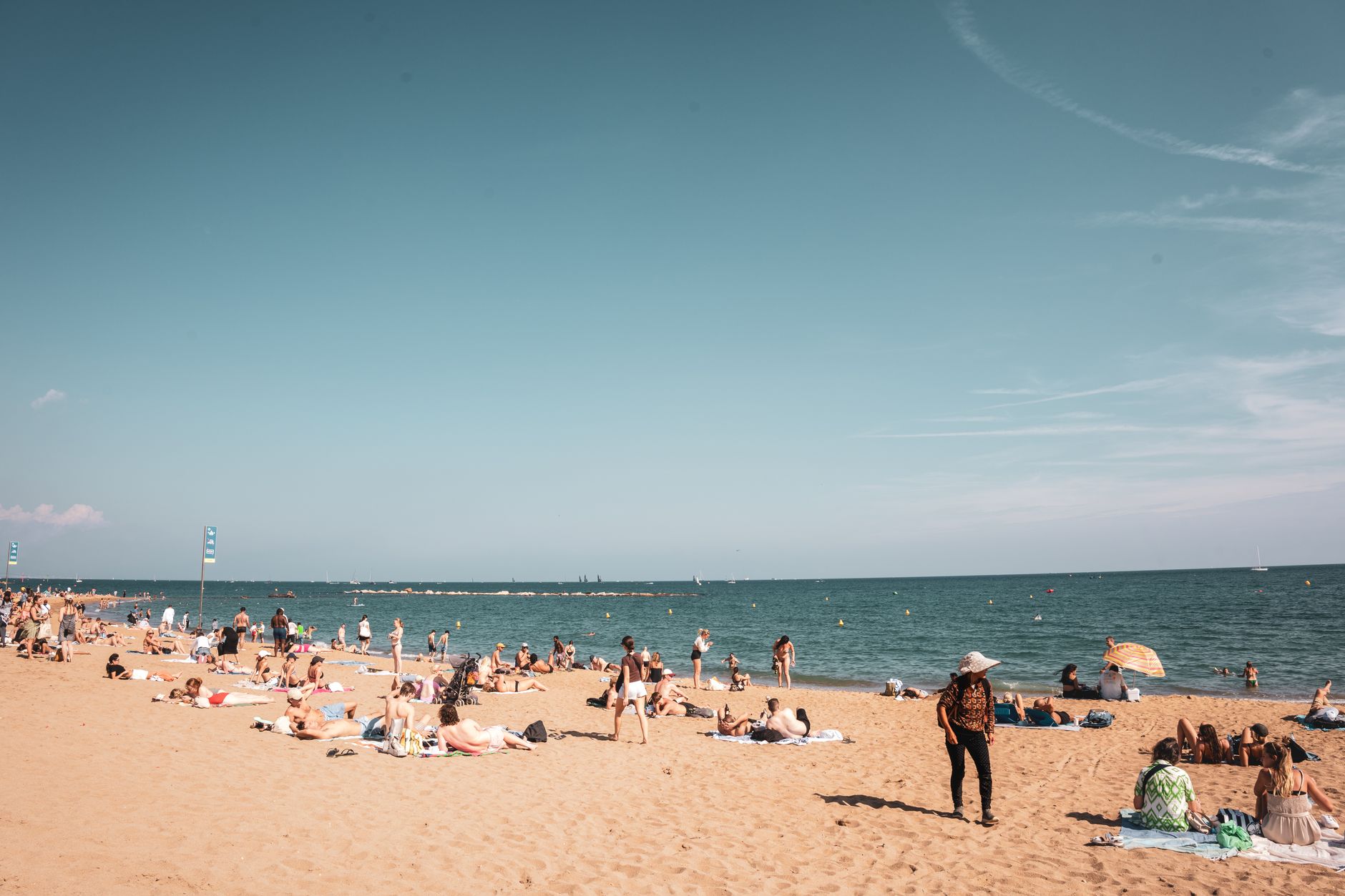 une journee ensoleillee et animee sur une plage de barcelone ou les gens profitent du sable et de la mer sous un ciel degage